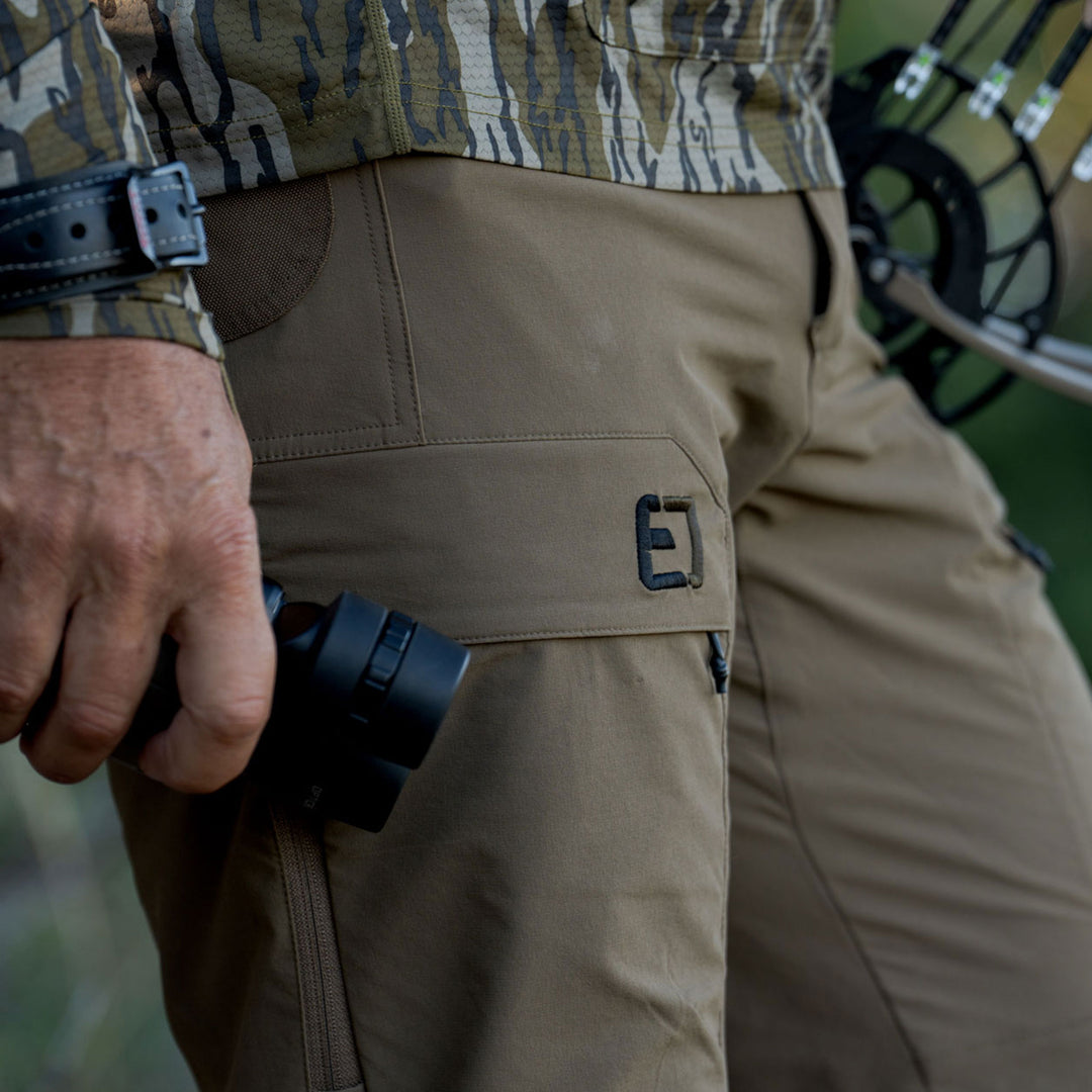 man holding binoculars by his side #color_coyote