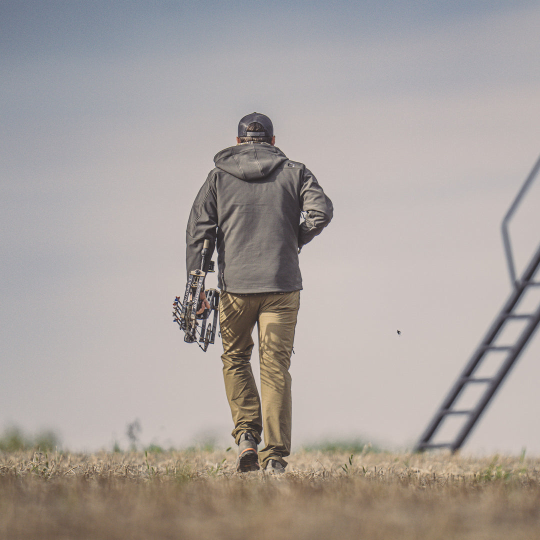 Hunter walking to a blind wearing peak series jacket#color_coyote